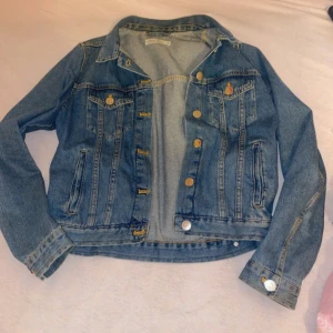 Blå jeansjacka - Snygg blå jeansjacka med klassisk design och knappar framtill. Jackan har två bröstfickor med knappdetaljer och långa ärmar. Perfekt för en avslappnad stil.
