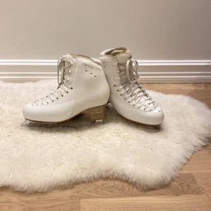 Vita konståkningsskridskor från Edea - Säljer ett par eleganta vita konståkningsskridskor från Edea. De har en klassisk design med snörning och är utrustade med MK-blad för optimal prestanda på isen. Perfekta för både nybörjare och erfarna åkare.