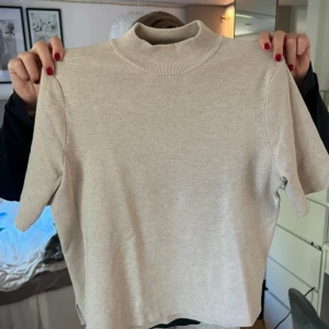 söt trekvarts ärmad tröja med liten krage  - Säljer en stilren beige polotröja med korta ärmar. Perfekt för en minimalistisk look och passar bra till både jeans och kjol. Tröjan har en mjuk och bekväm passform.