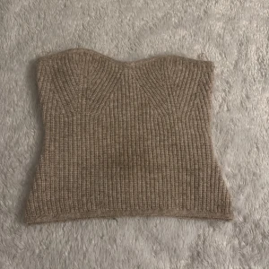 Beige ribbad tubtopp - Säljer en stilren beige ribbad tubtopp. Perfekt för en trendig look med sin figurnära passform. Toppen är ärmlös och har en mjuk och bekväm känsla. Passar utmärkt till både jeans och kjol.