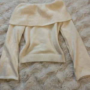 Vit offshoulder stickad tröja - Säljer en vit offshoulder tröja i stickat material. Tröjan har långa ärmar och en bred ribbad kant vid axlarna. Perfekt för kyligare dagar eller våren!🤍