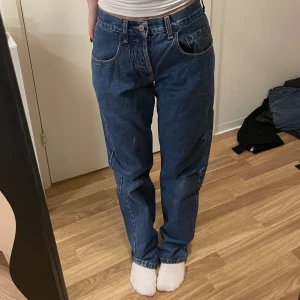 Blå jeans från Jack & Jones - Säljer ett par klassiska blå jeans från Jack & Jones i modellen Stanley. De har en straight passform och är högmidjade med knappar i gylfen. Perfekta för en avslappnad stil.