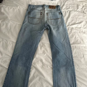 Ljusblå jeansbyxor - Snygga ljusblå jeans med klassisk femficksdesign och knappgylf. Perfekta för en avslappnad stil. De har en rak passform och är tillverkade i ett slitstarkt denimtyg.