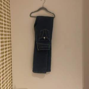 Snygga bootcut we mörkblå jeans med en unik fickdetalj på baksidan. Perfekta för en casual look med en stilren design. Passar bra till både sneakers och kängor.