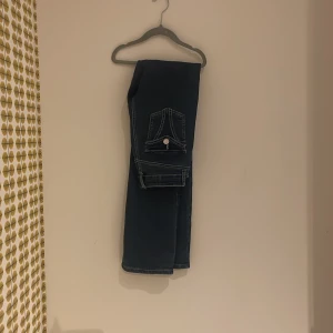 Mörkblå jeans med fickdetalj - Snygga bootcut we mörkblå jeans med en unik fickdetalj på baksidan. Perfekta för en casual look med en stilren design. Passar bra till både sneakers och kängor.