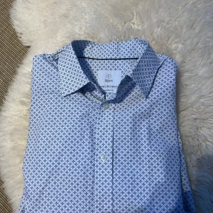 Vit och blå mönstrad skjorta från Bläck - Säljer en  vit och blå mönstrad skjorta från Bläck i bra skick. Storlek M/40