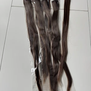 Brun hårförlängning med clips - Säljer en uppsättning bruna hårförlängningar med clips. Perfekt för att snabbt och enkelt få längre och fylligare hår. Färgen är en naturlig brun nyans som smälter in fint med de flesta hårfärger. Clipsen gör det enkelt att fästa och ta bort förlängningarna utan att skada ditt eget hår.