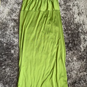 Grön långkjol - Säljer en härlig grön långkjol i storlek XXL. Kjolen har en enkel och stilren design, perfekt för både vardag och festliga tillfällen. Den är gjord i ett mjukt och bekvämt material som faller fint längs benen. Passar perfekt till sommardagar eller som en färgglad touch under hösten.
