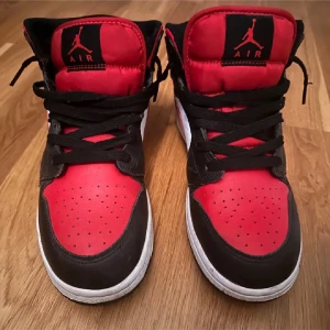 Nike Air Jordans i svart och rött - Säljer ett par snygga Nike Air Jordans i svart och rött. De har en klassisk design med svart snörning och den ikoniska Air Jordan-loggan på sidan. Skorna är i bra skick och perfekta för både vardag och fest. Passar dig som vill ha en stilren och sportig look!
