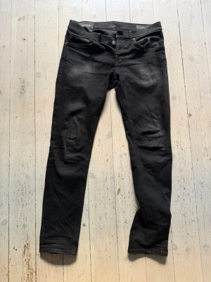 Dondup jeans - Snygga svarta slim fit jeans från Dondup, modell George. Jeansen har klassisk femficksdesign, knappgylf och diskreta slitningar framtill för en cool look. Tillverkade i stretchigt material för extra komfort.