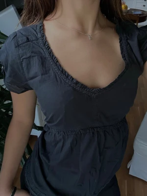 Svart blus från Odd Molly - Snygg svart blus från Odd Molly i storlek 2. Blusen har korta ärmar, v-ringning och fina spetsdetaljer längs kanterna. Perfekt till både vardag och fest! 