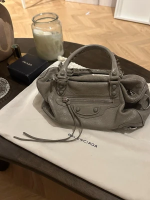 Grå Balenciaga handväska i skinn - Säljer denna Balenciaga väskan som tyvärr inte kommer till användning längre🤍är i en så unik fin grå färg! Längre band medkommer.
