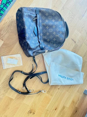 Superfin monogram ryggsäck väska - Snygg ryggsäck i klassiskt brunt monogrammönster. Mycket fin kvaliteväska som ska vara bra kvalité. Sammet innuti dustbag ingår väskan är oanvänd men en mini prick finns vid ena hörnan