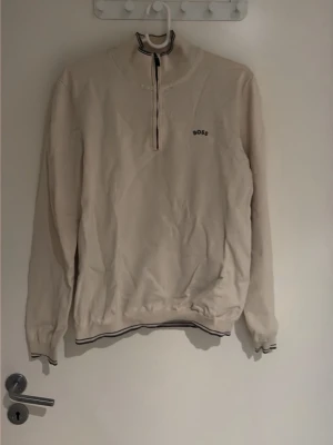 Quarterzip ifrån Boss - En beige golf quarter-zip ifrån Boss, med grå detaljer. Skrynklig på grund av att den inte använts på länge, fortfarande i gott skick. I skador/fläckar. 