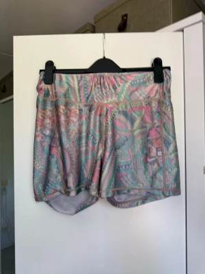 Mönstrade pastellfärgade träningsshorts shorts - Säljer ett par färgglada shorts med pastelligt mönster i rosa, blått och grönt. Shortsen har elastisk midja och är perfekta för träning eller sommarhäng. Lätta och bekväma med snygg design. Från märket Odd Molly i storlek 3 som enligt deras storlekguide motsvarar en storlek L. Mycket fint skick, jag hittar inga synliga anmärkningar eller defekter. 