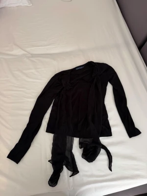 Svart transparent topp från Ralph Lauren - Säljer en elegant svart transparent topp från Ralph Lauren i storlek S. Toppen har långa ärmar och dekorativa knytband framtill. Perfekt att bära över ett linne eller som ett lagerplagg till fest eller vardag. Skickas nytvättad och i fint skick! 🌟