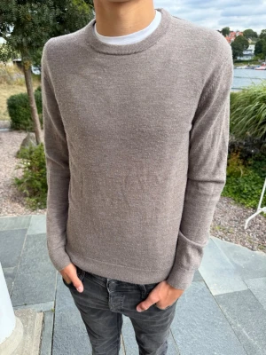 Beige stickad merinoulls tröja med rund hals - Säljer denna snygga merinoull tröjan från volt. Köpt för 699kr säljes för endast 349kr!