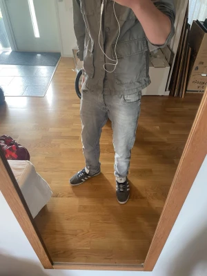 Ljusgråa raka jeans herr - Säljer ett par ljusgråa jeans med rak/slim passform och klassisk femficksdesign. Jeansen har en avslappnad look och är tillverkade i denim med lätt tvättad effekt. Perfekta för dig som gillar en enkel och stilren stil.