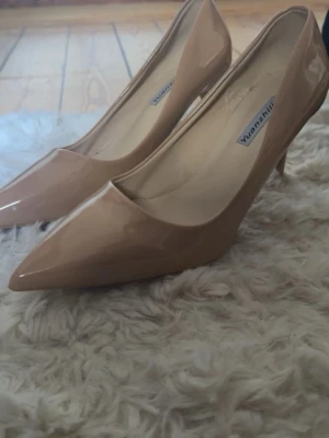 Beige lackade pumps med spetsig tå - Snygga beige pumps från Yuanzhnli i glansigt lackmaterial med spetsig tå och smal klack. Klassisk och elegant design