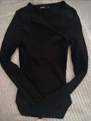 Svart långärmad topp med cut out - Trendig svart långärmad topp från Bik Bok med en snygg cut out-detalj vid halsen. Toppen är tight i modellen och har en rundad urringning. Perfekt för dig som gillar en stilren men edgy look.