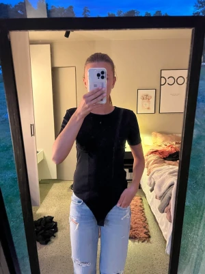 Svart kortärmad body - Snygg svart body med korta ärmar och rund hals. Modellen har en markerad söm under bysten och knäppning i grenen. Tillverkad i mjukt stretchigt material som sitter skönt mot kroppen. Perfekt att styla med jeans eller kjol. Nästan aldrig använd. Skriv för frågor 🩷🫶🏼