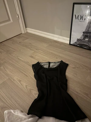 Svart ärmlös topp med diamanter  - Säljer en svart ärmlös topp med pärldetaljer längs halsringningen. Toppen har en lätt transparent look och en rundad hals. Perfekt att styla med både jeans och kjol för en trendig vibe.