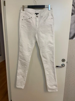 Vita skinny jeans från KappAhl, stl 40 oanvända  - Säljer ett par vita skinny jeans från KappAhl i storlek 40. Jeansen har klassisk femficksmodell, bälteshällor och silverfärgade nitar. Materialet är mjukt och stretchigt för en bekväm passform. Perfekta till en fräsch och stilren look.
