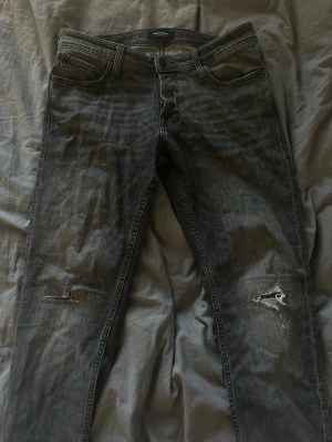 Mörkgrå jack and Jones slim glenn jeans med slitningar  - Mörkgrå Jack and Jones jeans med slitningar, säljs billigt.  
