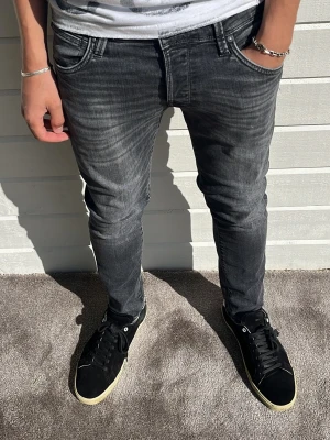 Jack & Jones jeans grå - Hej! Jack & Jones jeans med snygg tvätt! Modellen på bilden är 183cm och väger 68kg. Passformen heter Slim/glenn och har storleken W30/L30. 67% bomull 5% återvunnen bomull, 20% organic bomull 6% polyester och 2% elastan. Hör av dig vid intresse! 