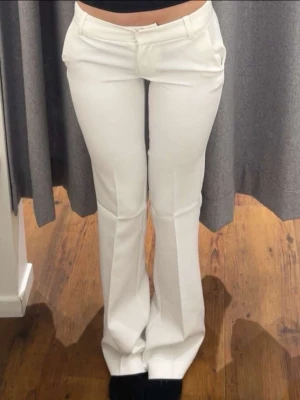 Vita utsvängda kostymbyxor - Snygga vita kostymbyxor med utsvängda ben och pressveck. Perfekta för en clean och stilren look. Wera tall 🥰dem är lite grå längtat ned till fötterna där bak men inget som syns när man har på sig dem för mestadels 💘
