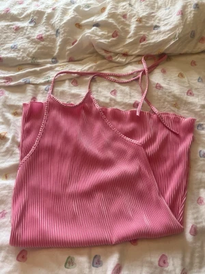 Rosa ribbad linnetopp från SHEIN - Säljer en söt rosa linnetopp från SHEIN i storlek S. Toppen har tunna axelband och är ribbad med ett plisserat tyg som ger en snygg struktur. Perfekt för varma dagar och enkel att styla med jeans eller kjol.