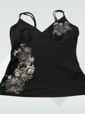 Svart linnetopp med broderade blommor - Snygg svart linnetopp med tunna axelband och v-ringning. Toppen har detaljerade broderade blommor i silverfärg på ena sidan och vid bysten.