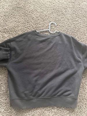 Svart sweatshirt från Pull&Bear - En svart sweatshirt från Pull&Bear i storlek M. Tröjan har en klassisk rund halsringning, ribbade muddar och är gjord i mjukt bomullsmaterial. Enkel och stilren design utan tryck eller detaljer, perfekt till vardagslooken.
