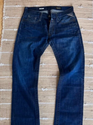 Mörkblå raka jeans - Snygga mörkblå jeans från replay med raka ben och klassisk femficksdesign. Jeansen har subtila slitningar och kontrastsömmar som ger en cool look. Tillverkade i denim med en tidlös passform som funkar till det mesta.