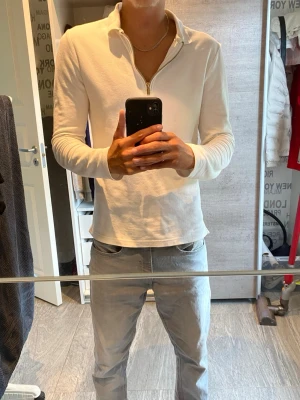 Vit långärmad polotopp med dragkedja - Snygg vit långärmad polotopp med dragkedja framtill. Toppen har en clean och enkel design med krage och är tillverkad i ett mjukt material som känns skönt mot huden. Perfekt för dig som gillar stilrena plagg med en modern touch. Fin tröja inte använt så mycket 