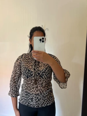 Leopardmönstrad blus från Gina Tricot - Leopardmönstrad blus från Gina Tricot, storlek 34. 🐆  ✨ Storlek: 34 ✨ Märke: Gina Tricot ✨ Färg: Beige/brun med svart leopardmönster ✨ Modell: Långärmad/3/4-ärm, volangdetaljer och knytning  