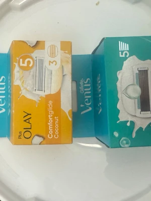 Gillette Venus rakblad ComfortGlide - Säljer två förpackningar Gillette Venus rakblad, ComfortGlide Coconut och ComfortGlide Pro. Ena förpackningen är gul och den andra turkos, båda med illustration av rakblad och märkta med 5 blad. Perfekt till Venus rakhyvlar.