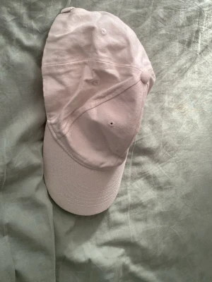Vit klassisk keps - Snygg vit keps i klassisk modell med böjd skärm och justerbar rem bak. Tillverkad i mjukt bomullstyg och har ventilationshål för extra komfort. Perfekt accessoar för en avslappnad och trendig look.