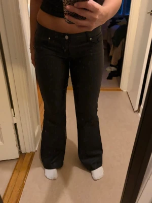 Svarta bootcut jeans - Snygga svarta bootcut skinnbyxor med klassisk femficksmodell och låg midja. Skinnbyxorna har en lätt utsvängd passform nedtill och stängs med knapp och dragkedja. Perfekta för dig som gillar en tidlös och trendig look.