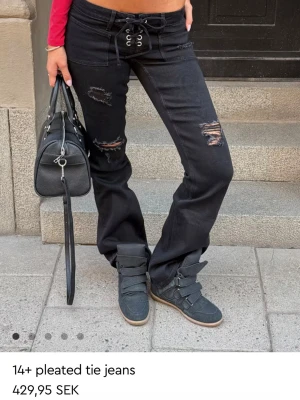 Snygga svarta low waist bootcut jeans - Säljer ett par super snygga svarta bootcut jeans med slitna detaljer Och ett snöre som knyte! Byxorna är helt slut sålda online och i butik. Trådarna i 2 av hålen vi knäna e borta men d är något som knappt märks medans trådarna vid hålet där uppe e kvar. De har lite slitningar nere på kanten längst ner vid hälen på jeansen eftersom det förekommit när jag gått runt med de men det är heller verkligen inget man lägger märke till. De passar perfekt till att styla upp en basic outfit!❤️😍❤️strl:xs tall