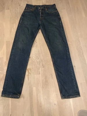 Mörkblå raka 501 Levi's jeans - Säljer ett par klassiska mörkblå Levi's jeans med rak passform. Jeansen har fem fickor, knappgylf och tydliga sömmar. Perfekta för dig som gillar tidlös stil och vill ha ett par jeans som funkar till allt.