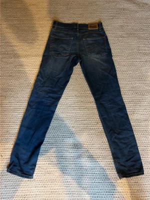 Blå Replay ZIKRY jeans - Säljer ett par blå slim fit replay jeans då de har blivit för små men de är perfekta för dig som vill ha en mer stilren och snygg outfit.