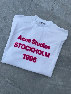 Acne Studios T-Shirt - Supersnygg Acne t-shirt till tjej med rosa fluffig text. Storlek S. Passformen är oversized/baggy. Alltså en avslappnad luftig passform, passar därför också större storlek. Perfekt att matcha till trendiga outfits. Skickar snabbt! ✨🤍