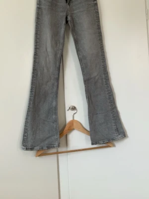 Grå utsvängda jeans Gina Tricot - Säljer ett par grå jeans från Gina Tricot med utsvängda ben och klassisk femficksmodell. Jeansen har hög midja och är tillverkade i ett mjukt denimtyg. Perfekta för dig som gillar retrostil och vill ha ett par riktigt snygga jeans med cool tvätt.