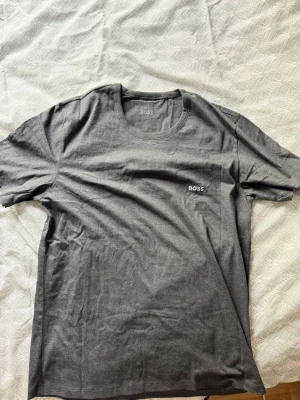 Grå BOSS t-shirt i bomull - Snygg grå t-shirt från BOSS med diskret logga broderad på bröstet. Klassisk rund halsringning och korta ärmar. Tillverkad i mjuk bomull för en skön känsla och enkel stil. Använd en gång!