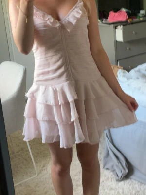 Ljusrosa volangklänning - Skitsnygg ljusrosa klänning från H&M, med volanger och lite uppsydd i axlarna för bättre passform. Använd 1-2 gånger💓