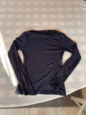  Långärmad topp - En enkel mörkblå långärmad topp. Tunn och mjuk i materialet, perfekt att styla lager på lager eller bära som den är. Passformen är ganska tight.