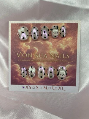 Puppy 🐶 (XS);ExtraShortOval  - Set handgjorda press-on naglar med vit glittrig bas, pink chrome,  svartprickiga. Några naglar har 3D-detaljer som rosett och gullig hund. Perfekt för dig som vill ha något unikt och lekfullt på naglarna!XS: 14 mm, 11 mm, 11,5 mm, 10 mm, 8 mm, i en extra short ovalform.