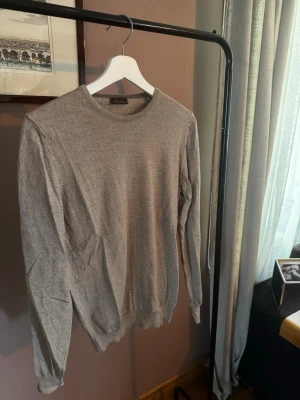 Beige stickad tröja från Stenströms - Snygg och stilren grå stickad tröja från Stenströms. Tröjan har rund halsringning, långa ärmar och ribbade muddar vid ärmslut och nederkant. Perfekt att matcha med jeans eller chinos för en clean look.