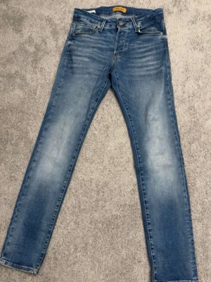 Jack and Jones jeans slim glen 28/30 - Säljer ett par blå slim fit jeans med lätt slitna detaljer och klassisk femficksdesign. W28 L30 knappt andvända i passform slim glen. Pris kan såklart diskuteras